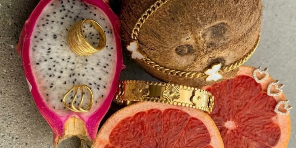 Les cinq pièces de la collection posées sur des fruits coupés : pitaya, noix de coco et pamplemousse